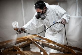 Uwe Weschenfelder mit Lackierpistole, Lackieranzug, Maske beim Lackieren einer Steinway & Sons Gussplatte